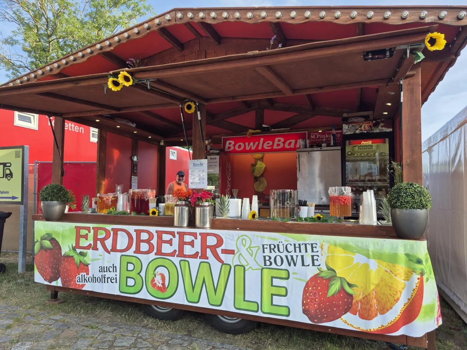 Holzhütte mit Erdbeer- und Früchtebowle, geschmückt mit Sonnenblumen